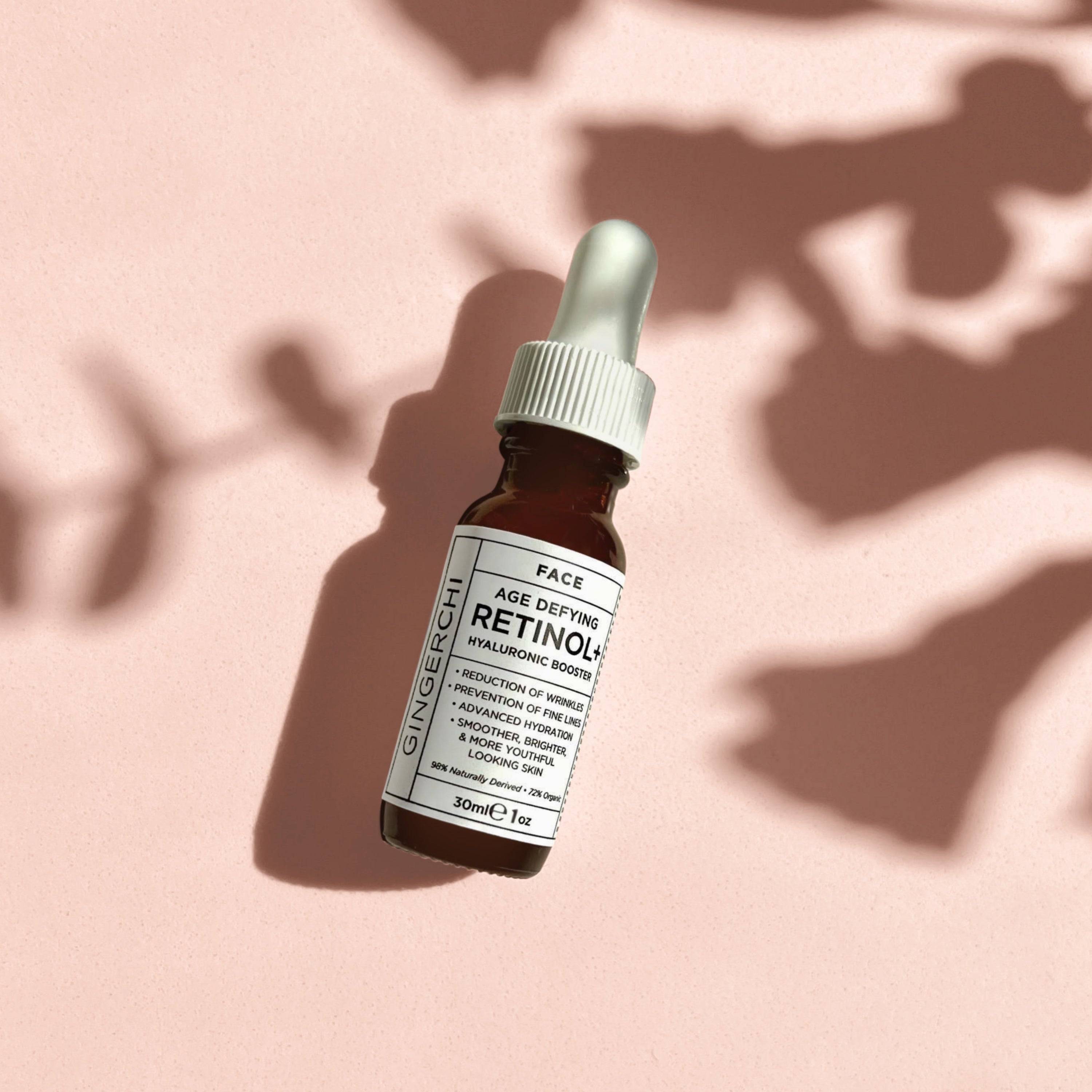 A bottle of GingerChi Age Defying Retinol+ serum with a dropper, placed on a surface with a shadow overhead.