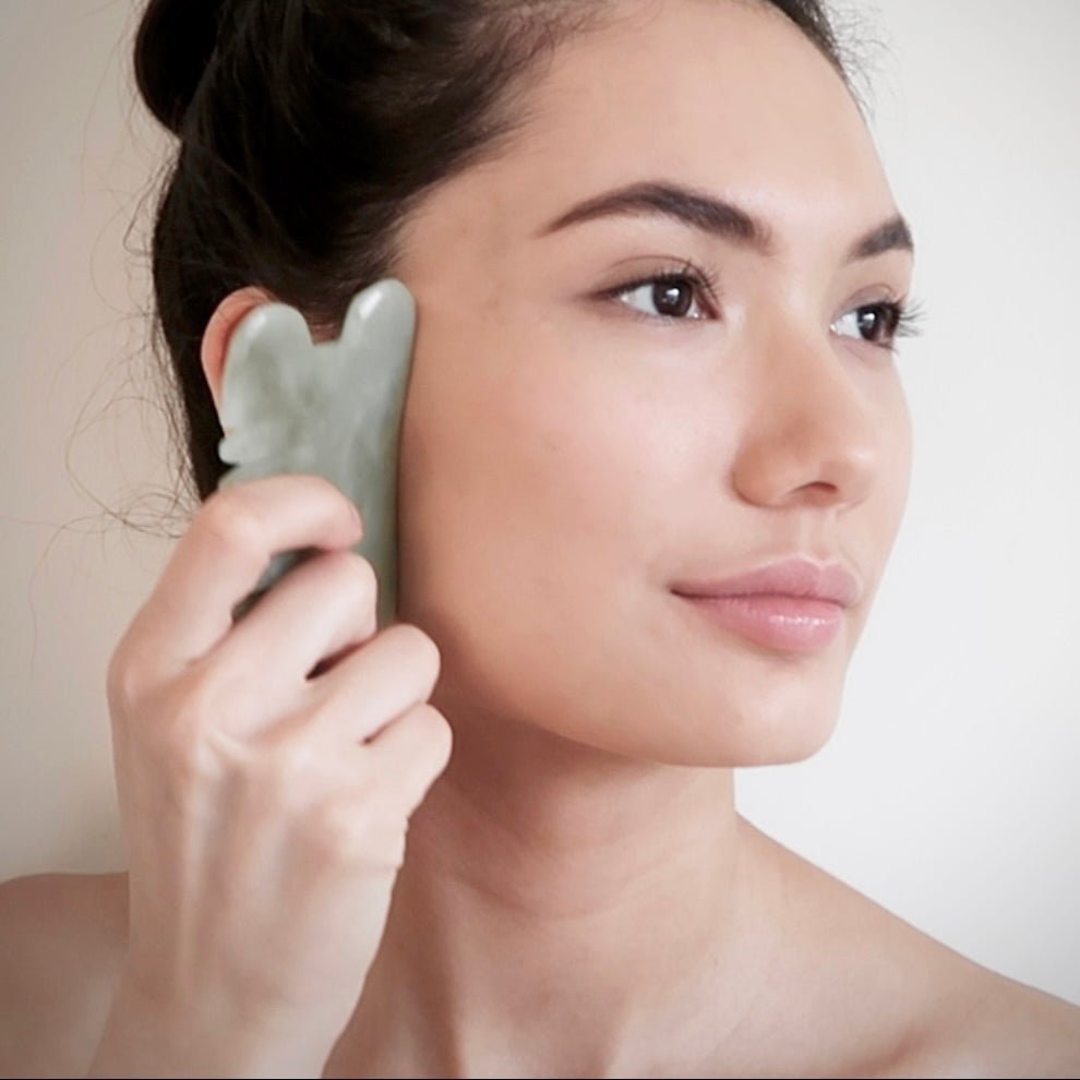 woman using jade Gua Sha tool on face for skincare