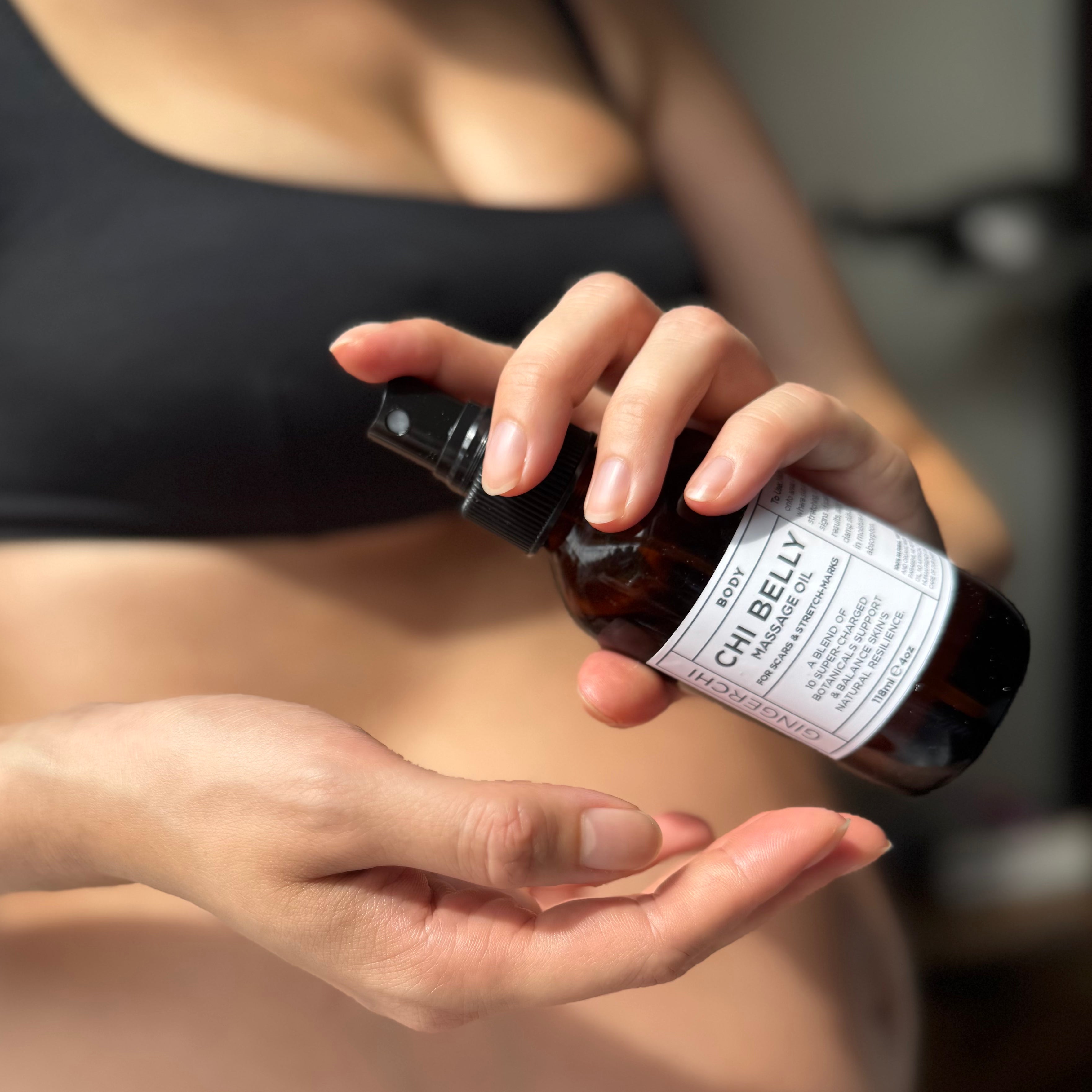 Hand holding a small dark glass bottle of Chi Belly Oil Mini