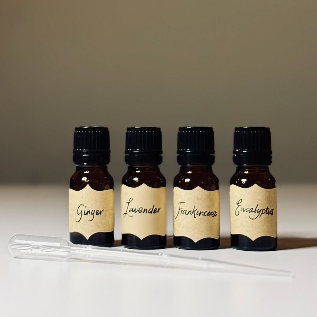 Essential oil bottles with handwritten labels for ginger, lavender, frankincense, and eucalyptus